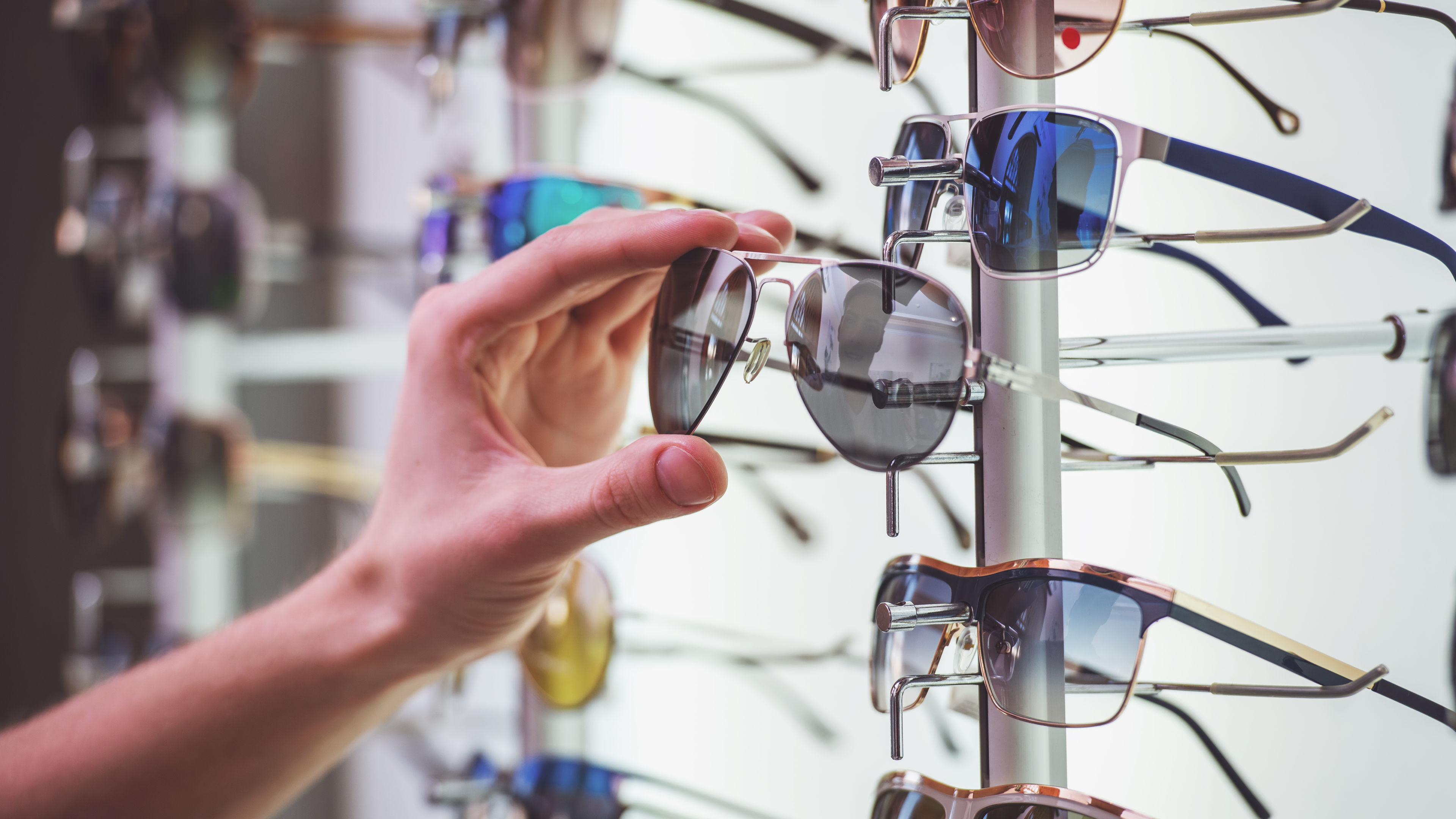 A hand is picking up a pair of sunglasses