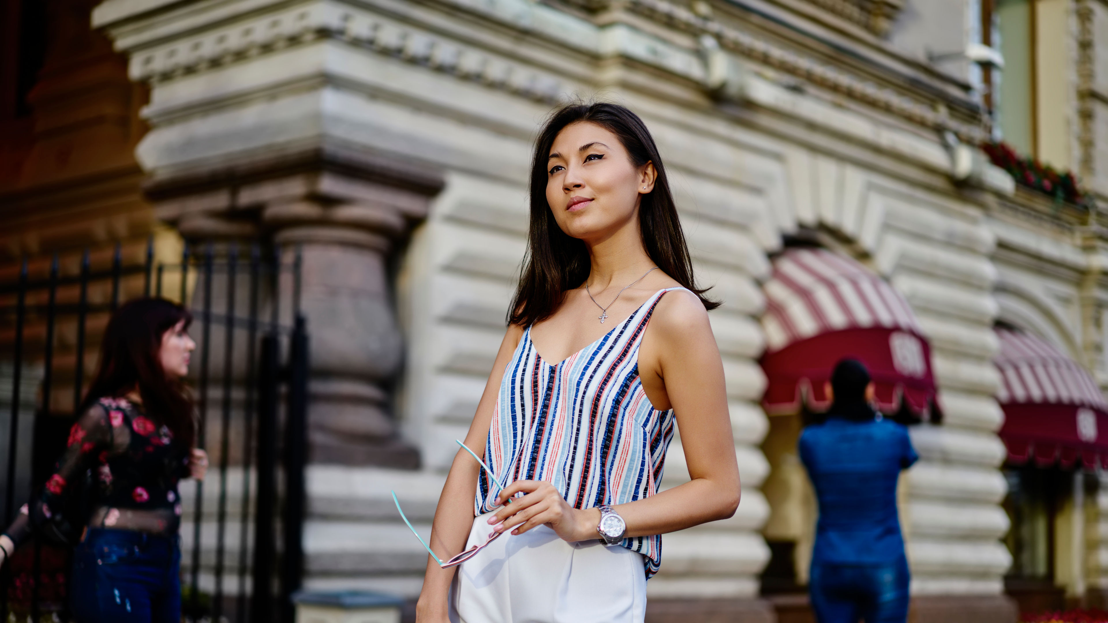 A woman holding a sunglass and looking thoughtfully.