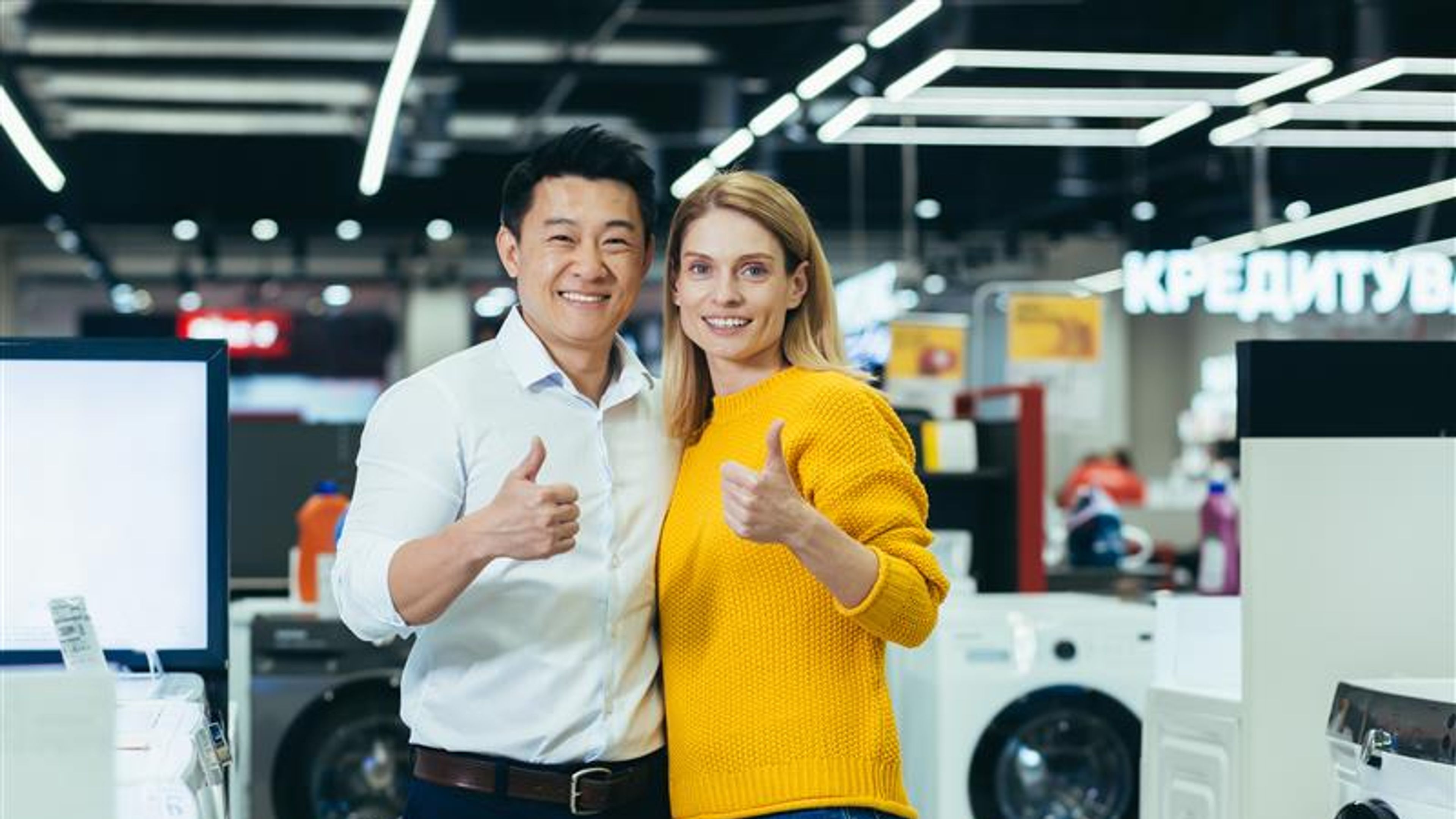 Satisfied diverse couple of shoppers Asian man and woman smiling and looking at camera