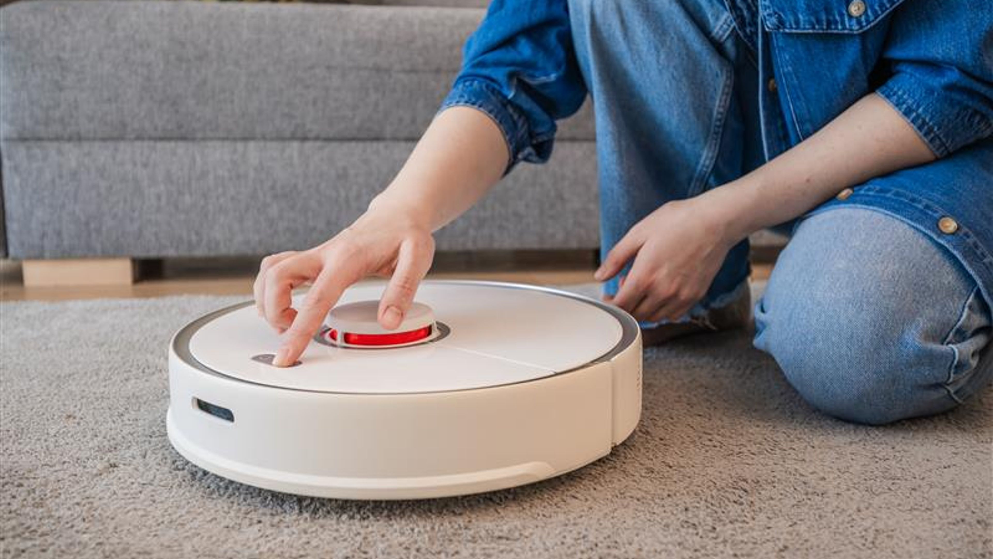 side view on woman turning on robot vacuum cleaner