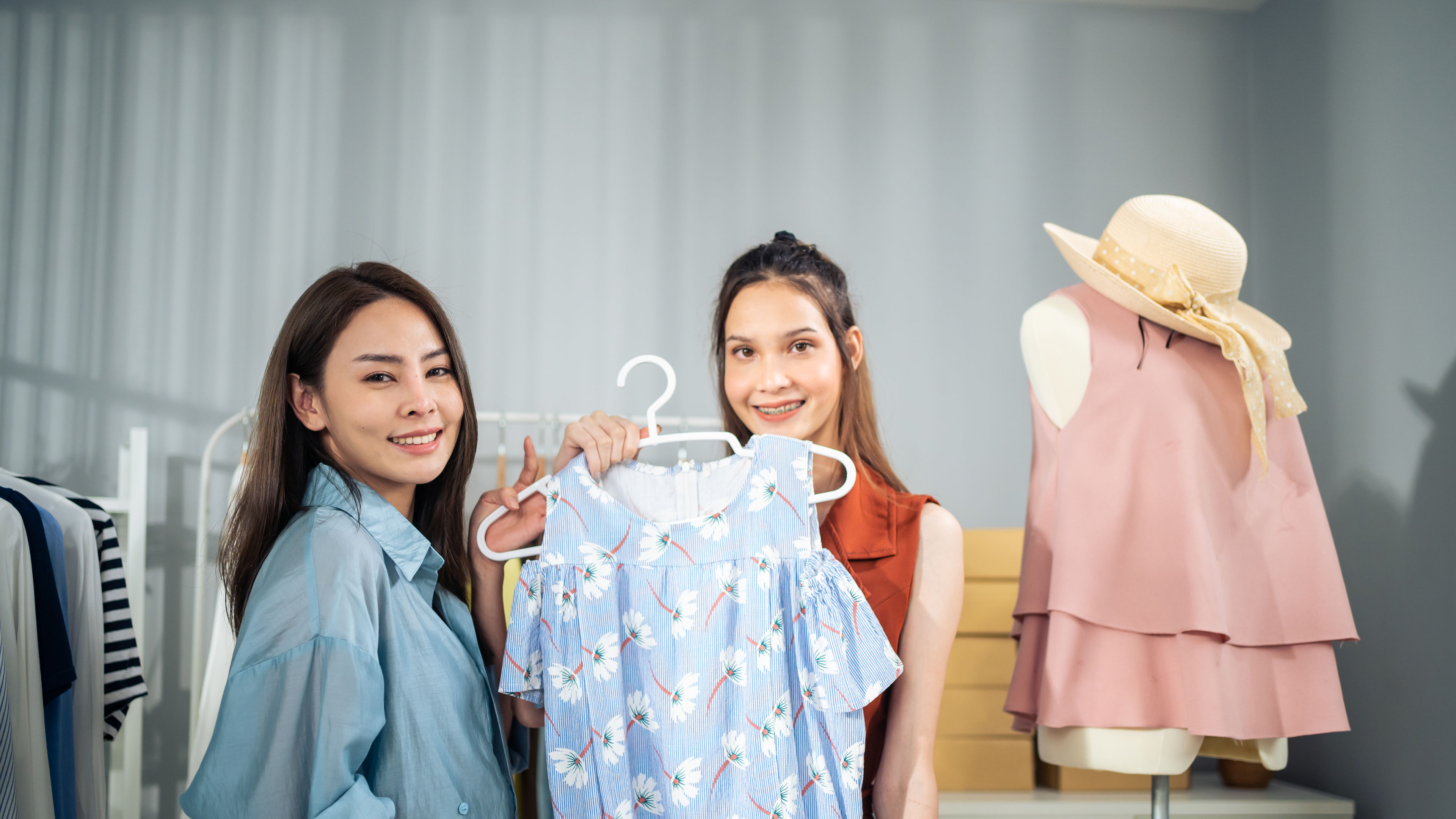 Two women are happily posing with clothing